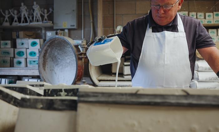 The photo shows a man pouring resin into a mould.
